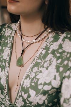 Close-up of a woman wearing layered necklaces with a floral dress.